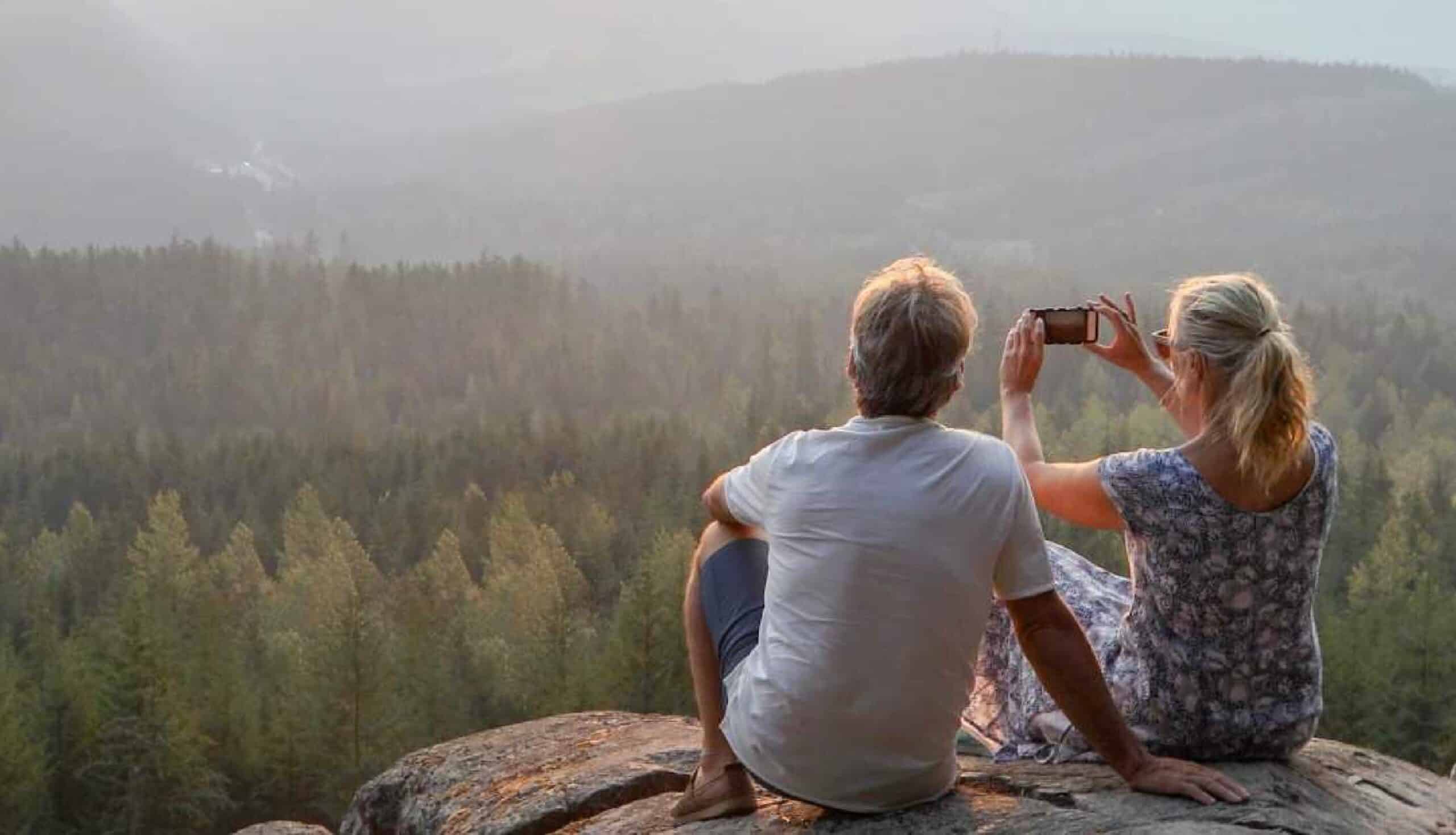 wealth planning corporation - retired couple looking in nature on vacation taking photo